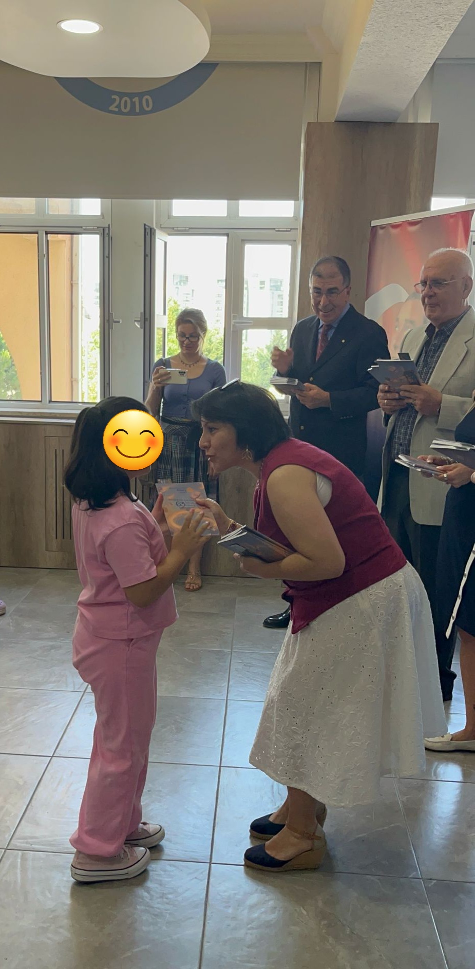 Hülya Biyan bir çocuğa kitabını teslim ederken
